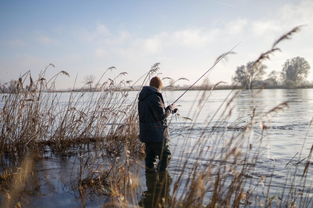 Eine Anglerin steht auf einer überschwemmten Buhne der Elbe.